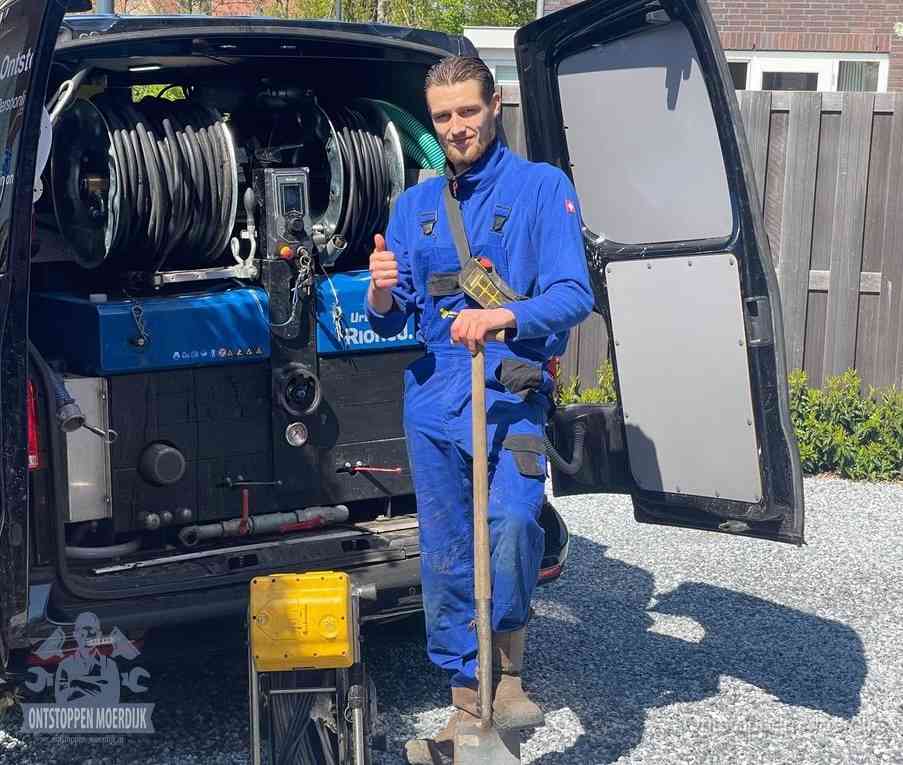 Een monteur bij de werkbus met grote hogedruk-slanghaspels, apparatuur voor hardnekkige afvoerverstoppingen in Moerdijk
