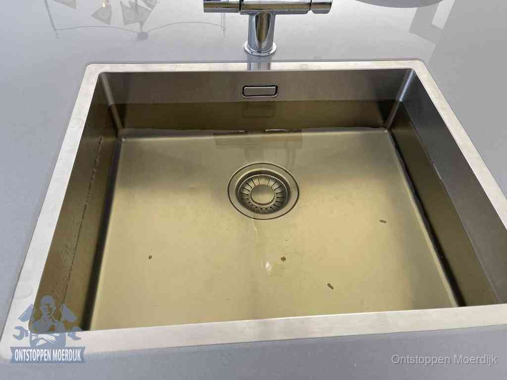 Stilstaand water in een rvs spoelbak dat niet wegloopt, een duidelijk signaal van een gootsteenverstopping in Moerdijk