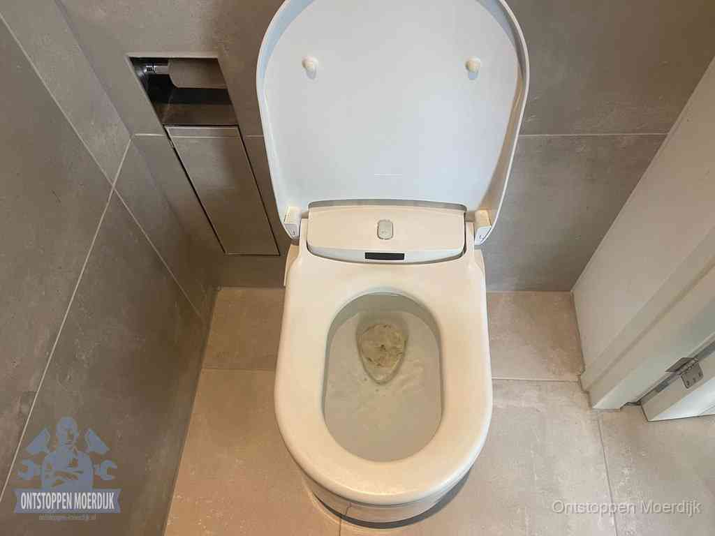Een wit hangtoilet waarin een prop wc-papier op het water blijft drijven, een duidelijk signaal van een verstopte wc in Moerdijk