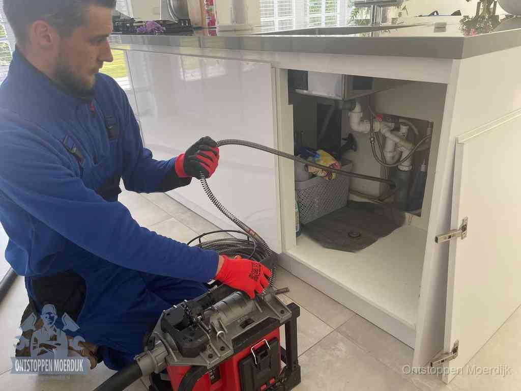 Een monteur reinigt de keukenafvoer grondig met een veermachine om terugkerende gootsteenverstoppingen te voorkomen in Moerdijk