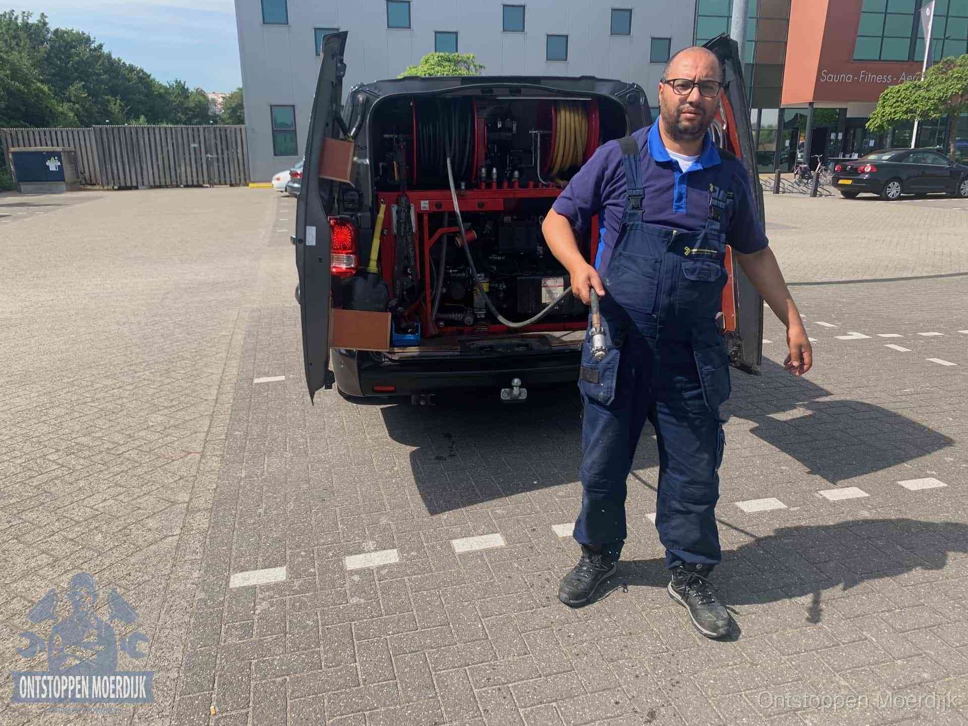 Een monteur bij zijn bestelbus met een hogedruk- en rioolreinigingsunit, klaar om de oorzaak van terugkerende wc-verstoppingen aan te pakken in Moerdijk