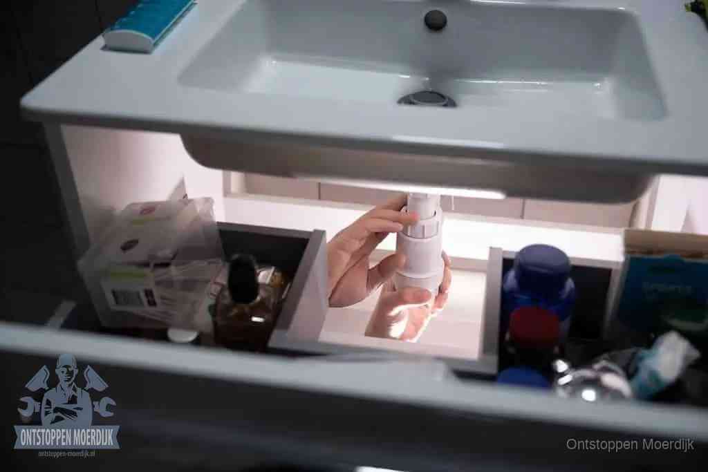 Een pompfles met zeep boven een wastafel in de toiletruimte, de warm water en afwasmiddel-methode om de wc te ontstoppen in Moerdijk