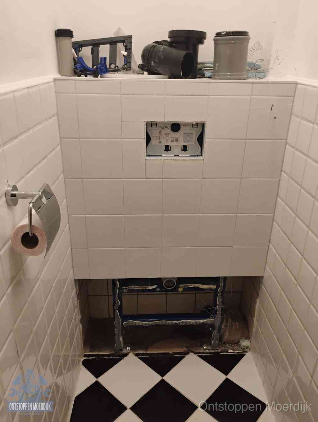 Een toiletruimte waar het hangtoilet en de inbouwreservoir-onderdelen zijn vrijgelegd voor onderhoud, periodiek nazicht voorkomt een wc-verstopping in Moerdijk