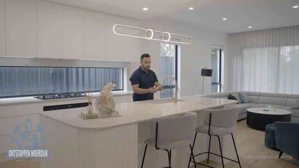 Een bewoner bij de keukenspoelbak die zelf aan de slag gaat met een verstopte gootsteen in Moerdijk